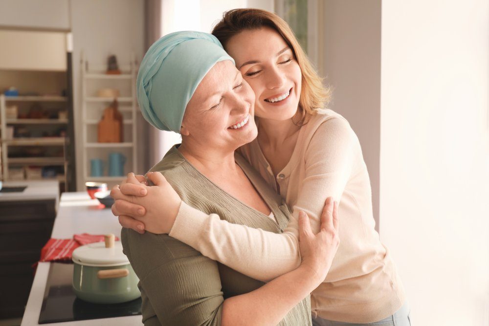 A woman hugs a lady suffering from medical hair loss.