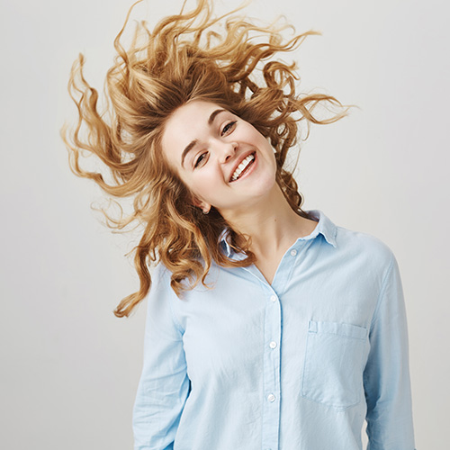 Laser Hair Therapy Client Testimonials. A woman with beautiful flowing hair tilts her head to the side.