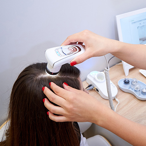 Laser Hair Therapy FAQ's. A Hair Tech uses a digital microscope to examine the hair follicles of a client.