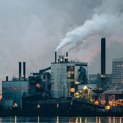 Hair Loss From Environment. A photo of a factory with many smokestacks and plumes of smoke going into the air.