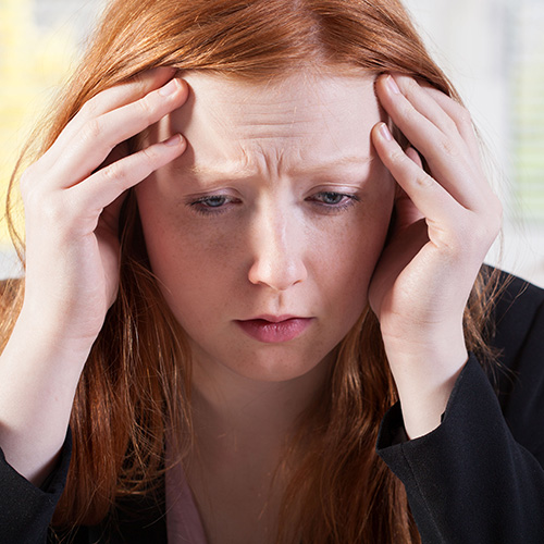 Hair Loss From Stress. A woman holds her hands to her head in stress.